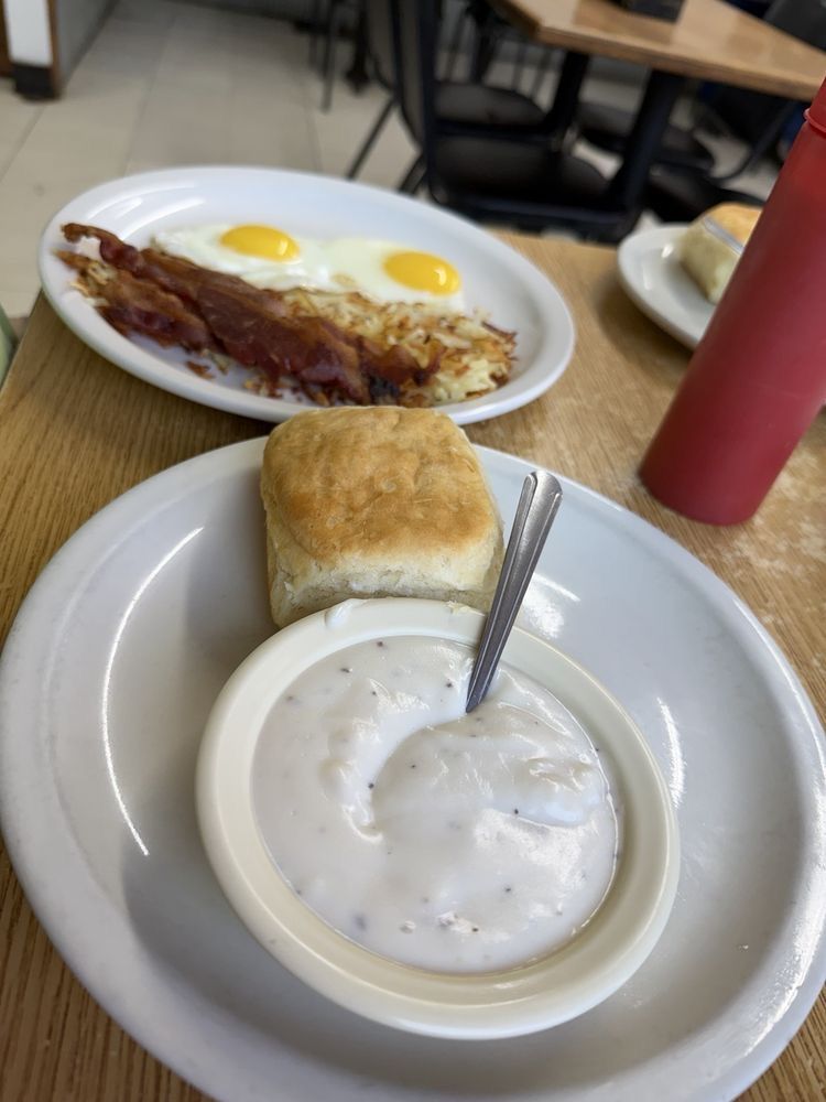 Biscuit and sausage gravy next to eggs, bacon and hash browns